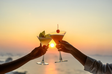Couple enjoying of Cheers glass of cocktail in a restaurant  at sunset view sea. Cocktail, Couple, Honeymoon, Dinner, Wine, Romantic concept.