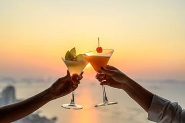 Couple enjoying of Cheers glass of cocktail in a restaurant  at sunset view sea. Cocktail, Couple, Honeymoon, Dinner, Wine, Romantic concept.