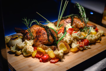 Close-up of a large turkey decorated with various vegetables around and served to a happy family on a flat wooden table. Chicken, turkey, vegetable, large, food, party, lifestyle concept.