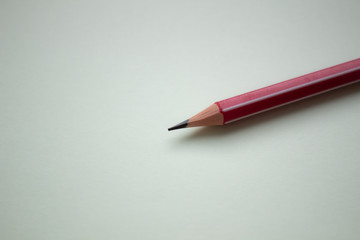 One red pencil on a light green background.