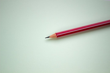 One red pencil on a light green background.