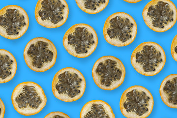 Colorful fruit pattern of granadilla or grenadia passion fruit cut in half on blue background from top view