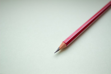 One red pencil on a light green background.