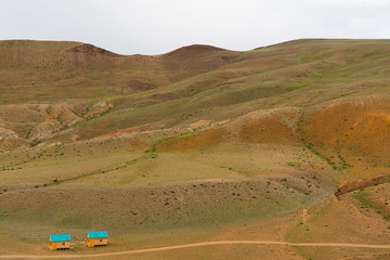 yellow hills and ravines in steppe, arid landscape under clouds, mountains with traces of soil erosion, pasture for goats and sheep