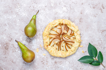 Homemade pear galette pie with almond leaves and fresh ripe green pears
