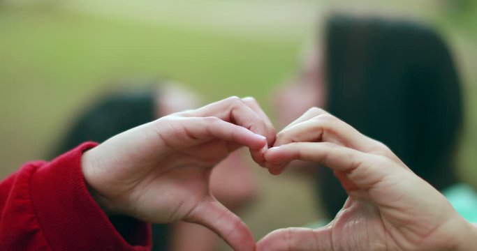 Lesbian lovers doing heart shape sign symbol with hands on a date. LGBT pride
