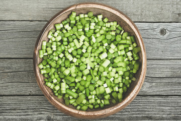 chopped green garlic stalks in wooden plate, cooking vegetarian dish, healthy food