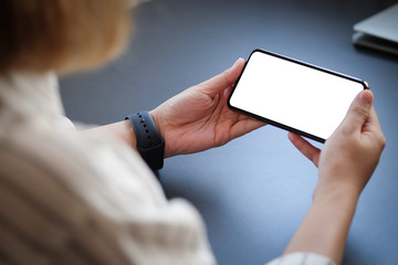 Cropped shot view of man hands holding smart phone with blank copy space screen for your text message or information content, female reading text message on cell telephone during in urban setting.
