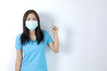 Asian women wear masks to prevent disease covid 19, long haired-black women. Wearing a blue collar shirt. Hand pointing up on white background.
