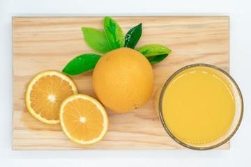  WHOLE ORANGES AND SLICED ON A WOODEN BOARD, TOGETHER WITH A JUICE OF ORANGE AND DECORATED WITH GREEN LEAVES AND A JUICE OF ORANGE.