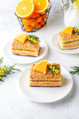 Orange cake decorated with fresh orange slices and mimosa flowers on light background