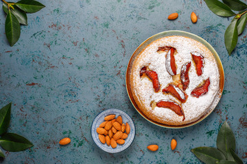 Fototapeta na wymiar Homemade rustic plum cake with powdered sugar and almond,top view