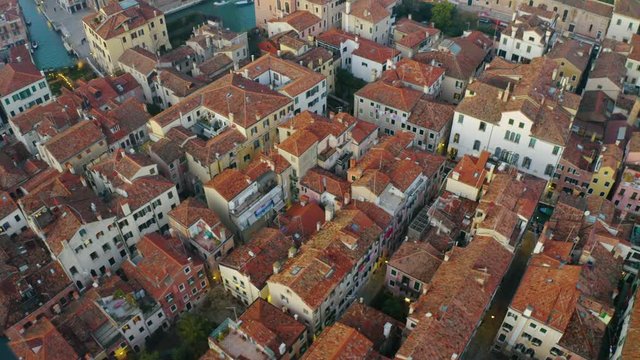 Aerial, tracking, drone shot over colorful buildings, in Venice city, at sunset, in Northern Italy