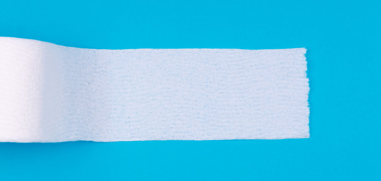 Toilet paper roll on the bright blue background. Coronavirus COVID-19 pandemic panic shopping, social distancing concept. Bright monochrome drop in wide screen banner format with place for text