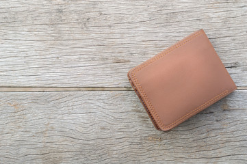Brown leather wallet placed on vintage wooden table. Financial concept, top view.