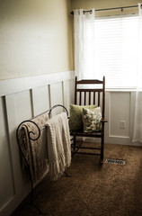 rocking chair and crocheted blankets in front of a window
