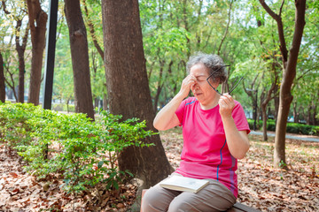 senior women have eye pain due to the reading book