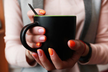 female hand with bright manicure holds a mug
