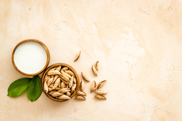 Fototapeta na wymiar Alternative milk made from almond. Drink near unpeeled on beige table top-down copy space