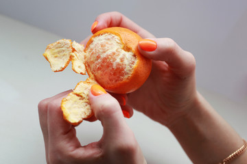 female hand with bright manicure holds a mandarin