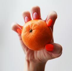 female hand with bright manicure holds a mandarin
