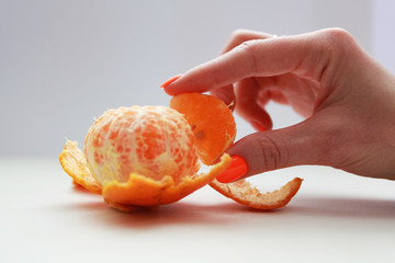 female hand with bright manicure holds a mandarin