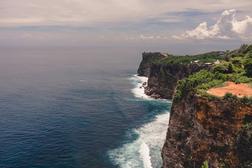 The beautiful nature of Indonesia and the island of Bali. Slopes and cliffs overlooking the waves of the blue ocean. Tropical and exotic view of travel to Asia