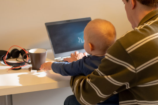 Coronavirus Lockdown Work From Home Concept. Close Op Of Hands Of A Man Working From Home With The Baby On His Laps.