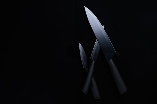 A black chef knife set on black background.