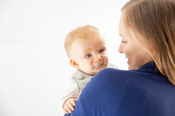 Mother carrying infant child. Beautiful happy young woman hugging adorable infant baby girl. Motherhood concept