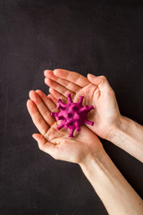 Corona virus Covid-19 - diagnostics concept with strain virus model and hands - on black background top-down