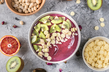 Healthy breakfast bowl: blueberry smoothie with kiwi, white chocolate and nuts
