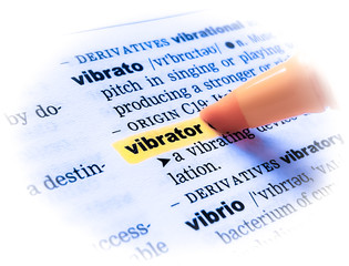 A close up of the word: VIBRATOR in a dictionary, highlighted in yellow and showing part of its definition.	