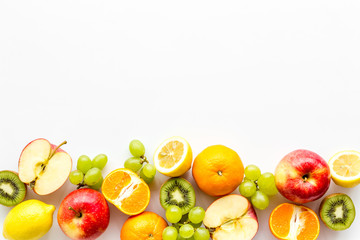Fresh fruits background with citruses, apple, kiwi and grape on white table top-down frame copy space