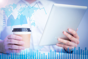 Businessman using tablet with financial analysis graphs. Close-up of man drinking coffee from disposable cup. Unrecognizable manager analyzing online report in office. Lifestyle concept