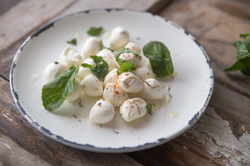 Mozzarella cheese balls in plate with mint . Traditional Italian food concept. Top view