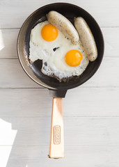 Fried eggs, sausage in iron pan -  Healthy food english breakfast