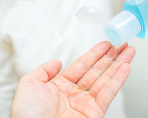 The woman's hand pouring alcohol gel from bottle to clean hands and prevent coronavirus infection,...