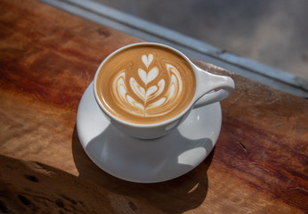 Close up of coffee cup with coffee latte art on a top. Latte art coffee over wooden background.