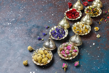 Assortment of dry tea in golden vintage mini plates.Tea types background:hibiscus,chamomile,mixed black tea,dry roses,butterfly pea tea