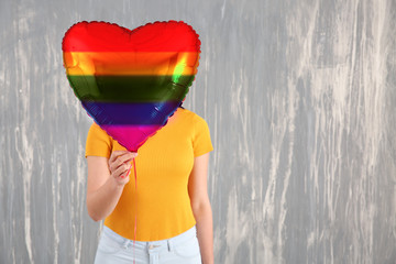 Young woman with rainbow air balloon against grunge wall. LGBT concept