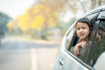 Cute girl sitting in car against blossom Tabebuia aurea tree background