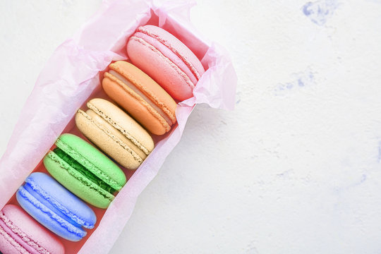 Box with different tasty macarons on white background
