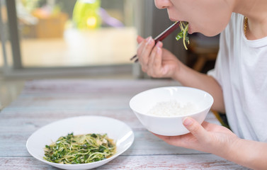 Asian girl eating rice and vegetable with bowl and chopsticks, 