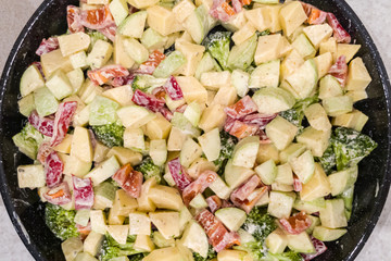 Finely chopped and seasoned vegetables for cooking in the oven. Potatoes, bell peppers, zucchini and broccoli. Healthy food close-up