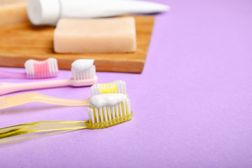 Tooth brushes with paste and soap on color background