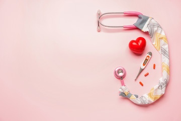 Stethoscope with cover, heart, pills and thermometer on color background