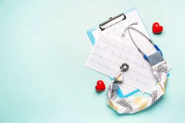Stethoscope with cover, hearts and cardiogram on color background