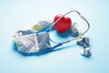 Stethoscope with cover and heart on color background