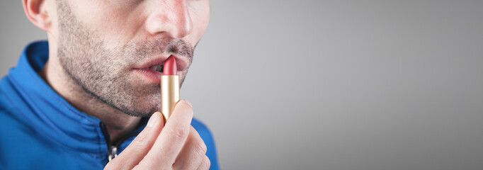 Man applying red lipstick on lips.